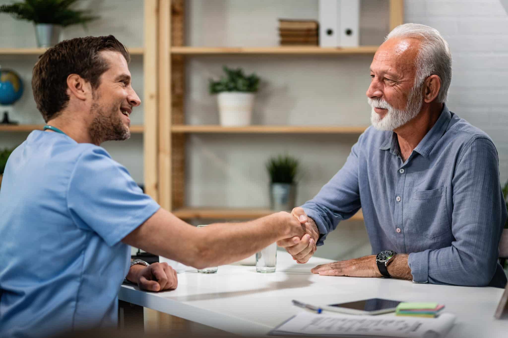 happy doctor greeting handshaking with senior patient his office focus is senior man scaled