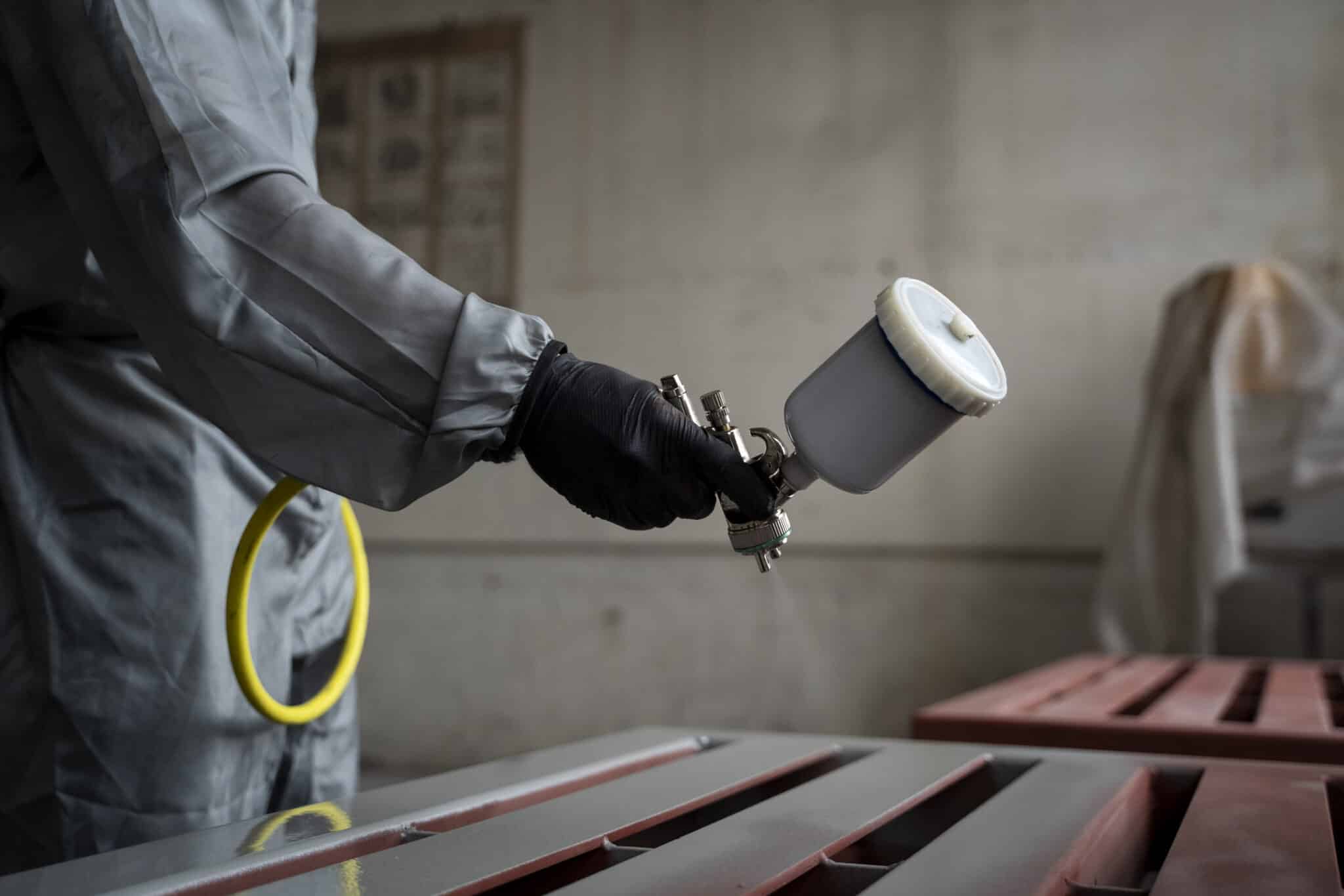 side view worker spraying powder paint from gun scaled